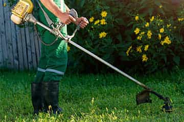 A man using a strimmer in a garden